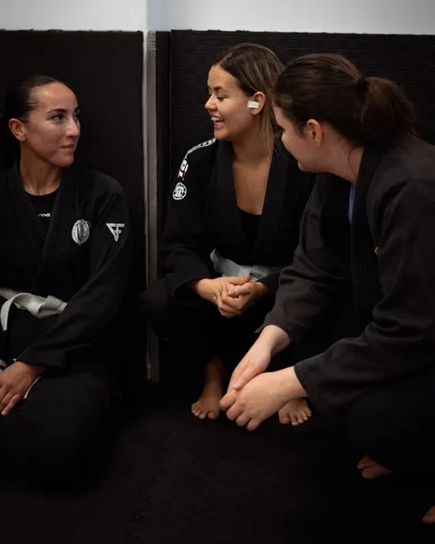 Three Under Pressure athletes in gi, sitting on the mat